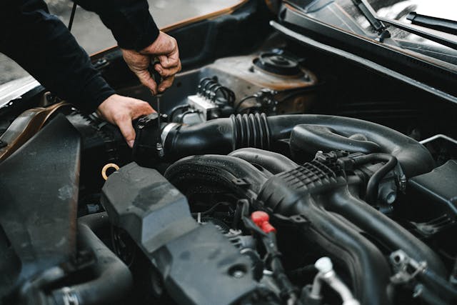 mechanic checking under the hood of a car